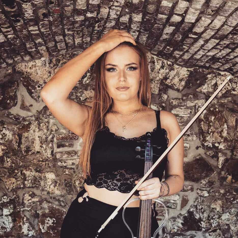 posing with violin in front of stone wall