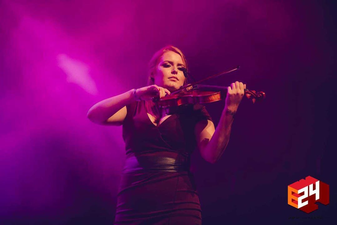 Ekaterina playing violin on a concert in a black dress