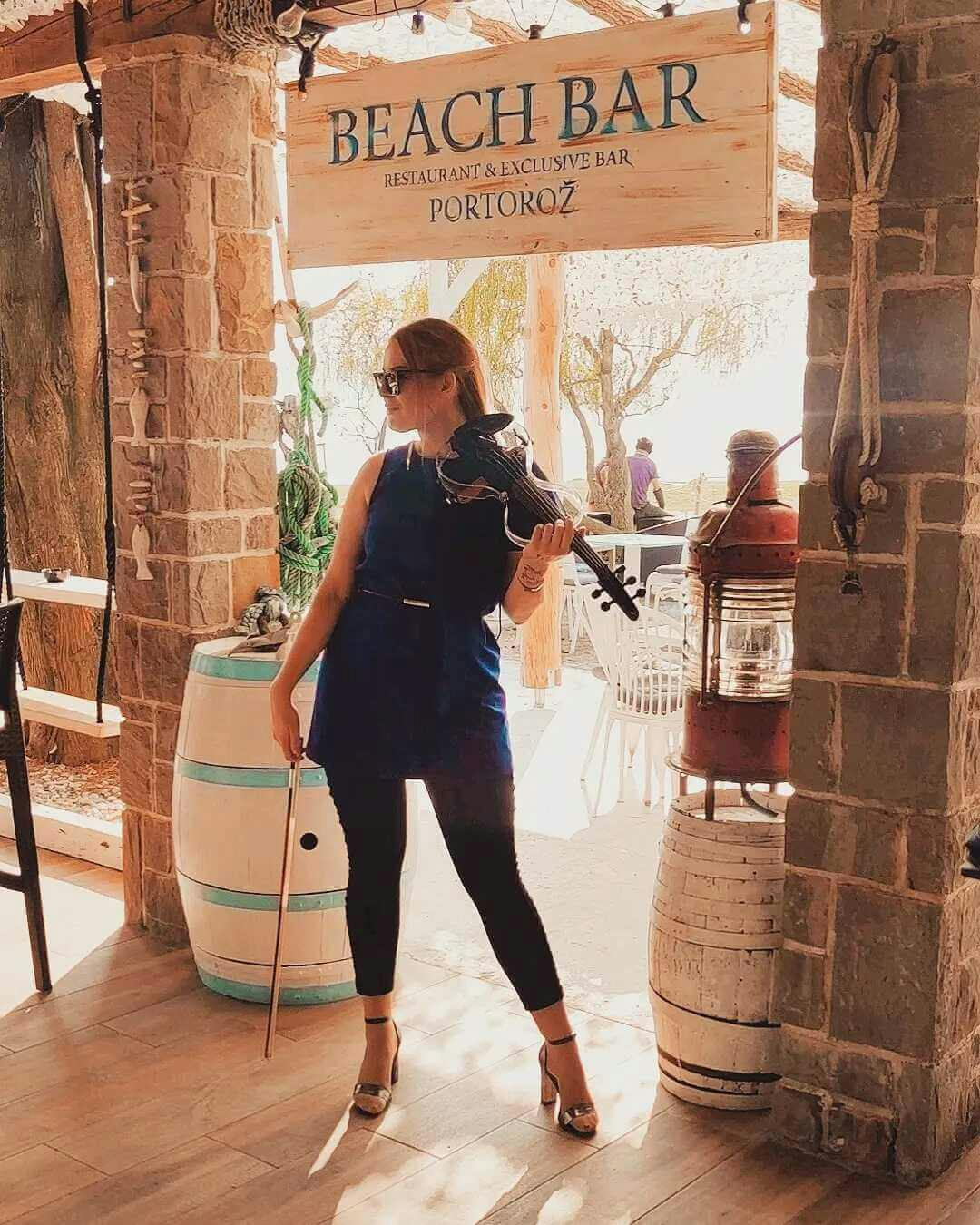 she is posing with violin in Beach bar Portorož