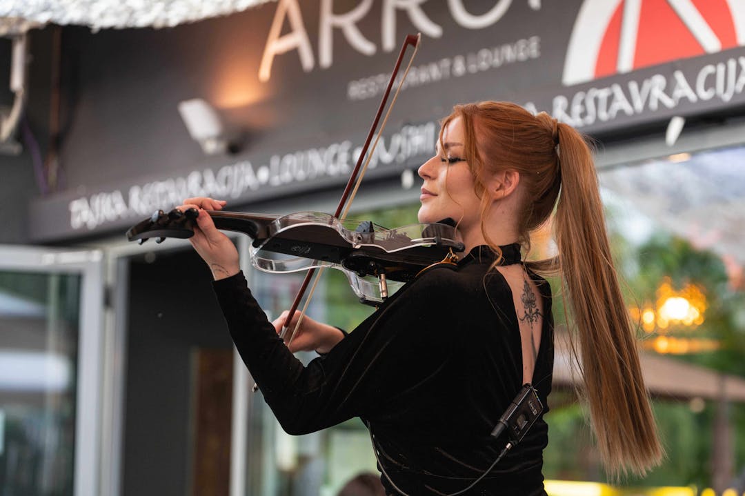 Ekaterina playing violin in front of the restaurant looking at people